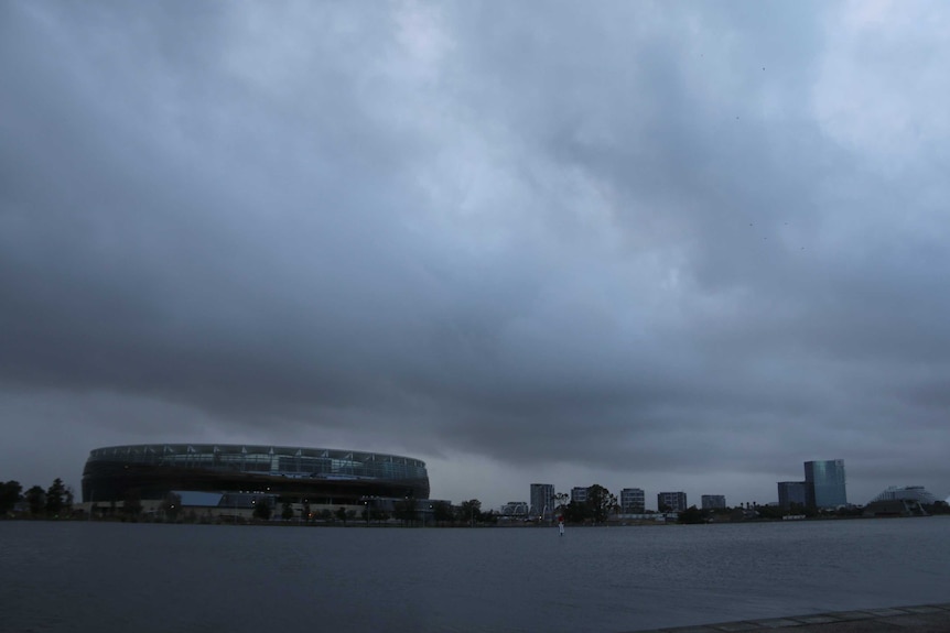 Dark rain clouds hang over Perth Stadium and high-rise buildings with the Swan River stretching out in front.