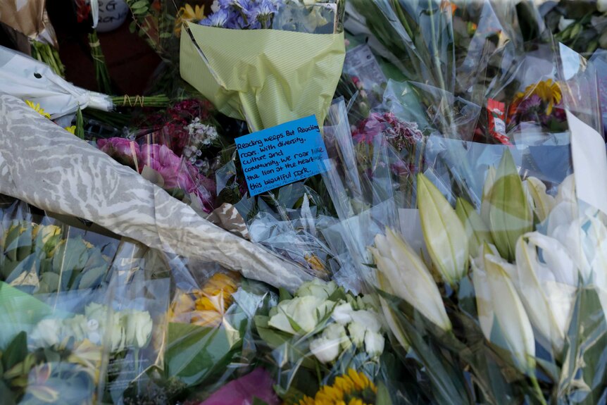 A written tribute lies with flowers placed beside a police cordon.
