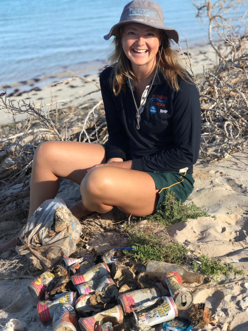 Emma Westlake sits on the beach with a pile of old rubbish she's collected