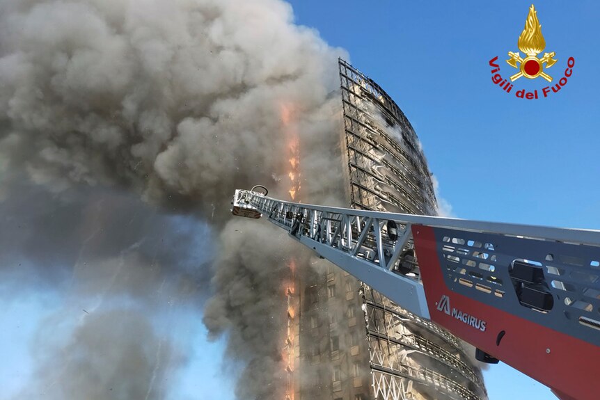 A tall building with smoke and fire vertically ripping through.