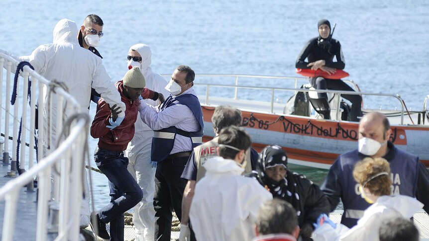 Rescued migrants disembark from an Italian coast guard boat in Palermo