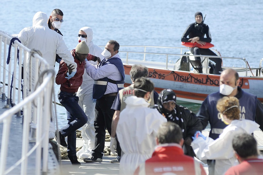 Rescued migrants disembark from an Italian coast guard boat in Palermo