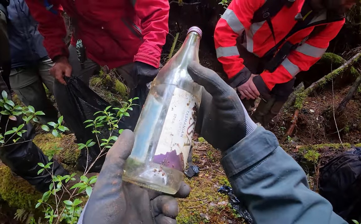 Um grupo de pessoas não identificadas olhando para uma garrafa de vidro.