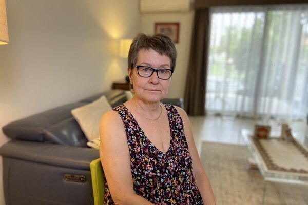 A woman with short hair and glasses sitting in a living room. 