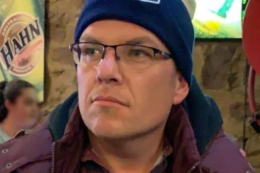 A man in a beanie wearing glasses.