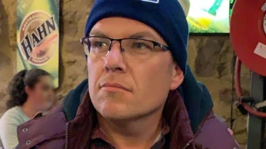 A man in a beanie wearing glasses.