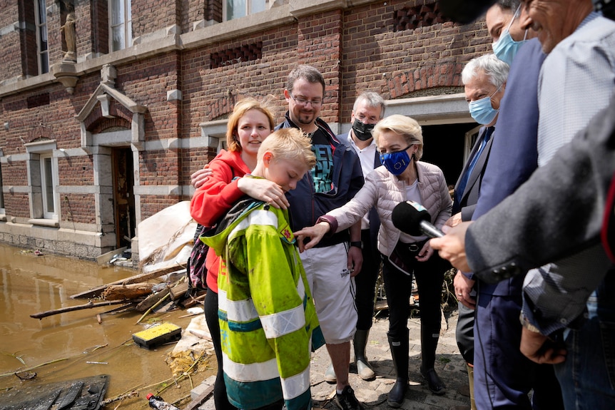 La présidente de la Commission européenne, Ursula von der Leyen, s'adresse à une famille entourée de médias à l'extérieur d'une maison endommagée par les inondations. 