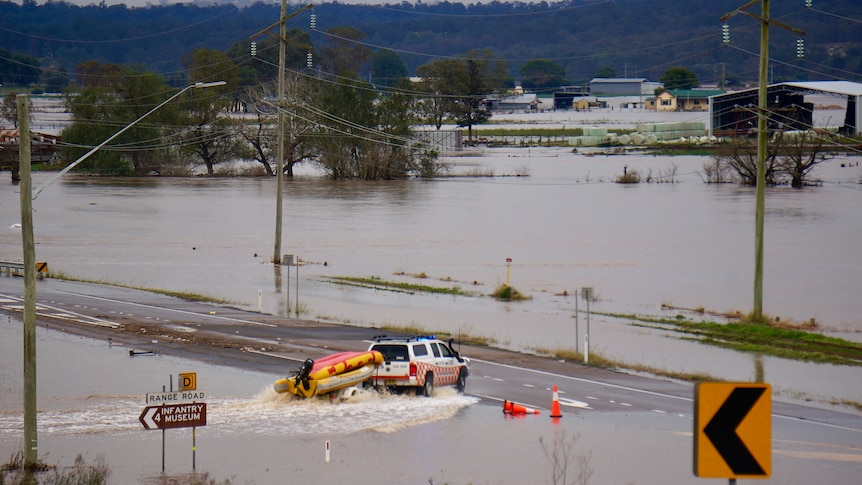 An SES truck tows a rescue boat through floodwaters near Singleton.