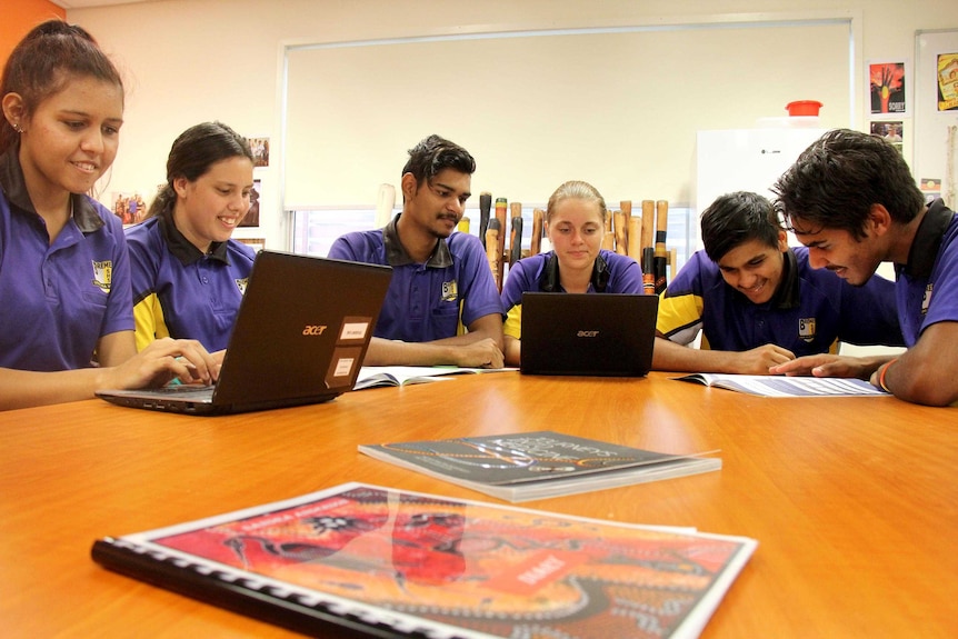 Indigenous students look over their work at a table in a classroom at Bremer State High School.