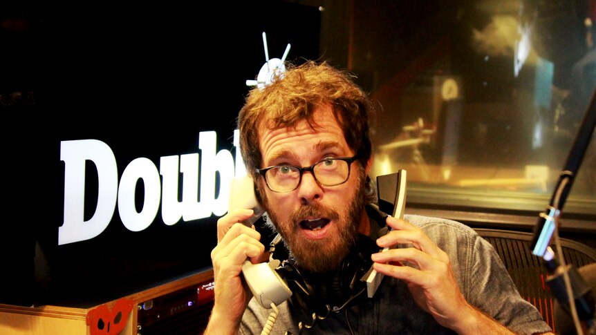 Ben Folds in the Double J studios pretending to talk on the phone with a surprised look on his face