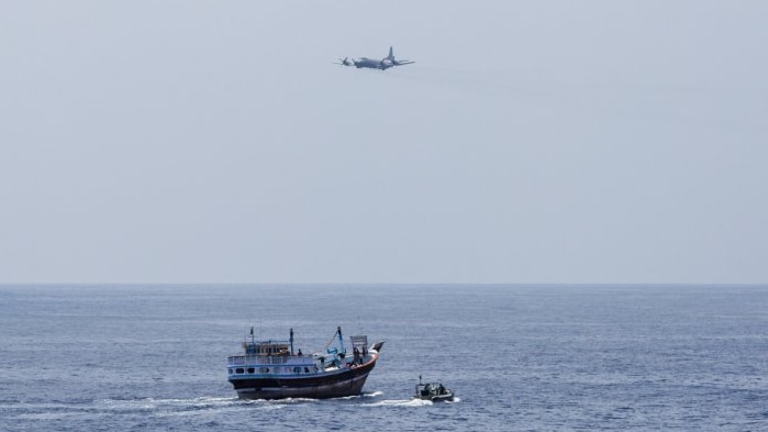 A Royal New Zealand Air Force P-3K2 Orion flies past HMAS Warramunga's boarding team.