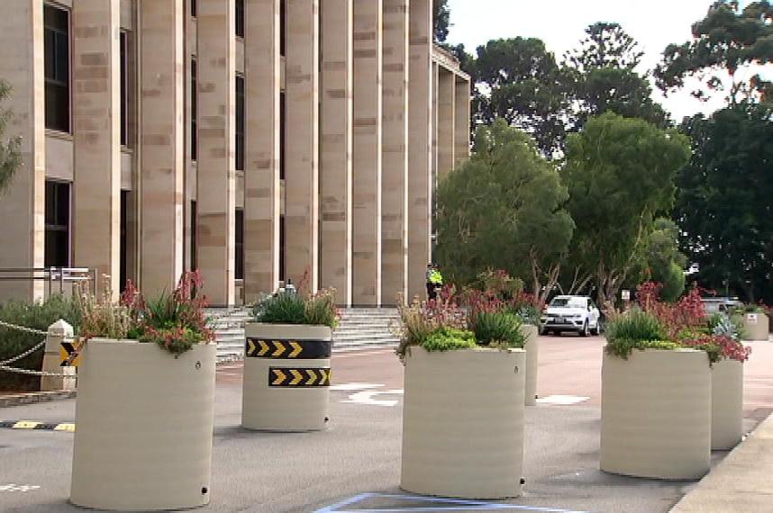 Security bollards out the front of WA's Parliament House with two police guards in the background.