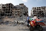 Palestinian men ride a donkey cart past destroyed buildings in the northern Gaza Strip on August 5, 2014.
