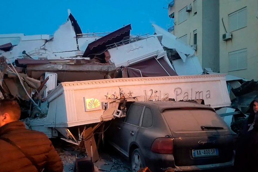 Buildings collapse onto cars and people during the earthquake.