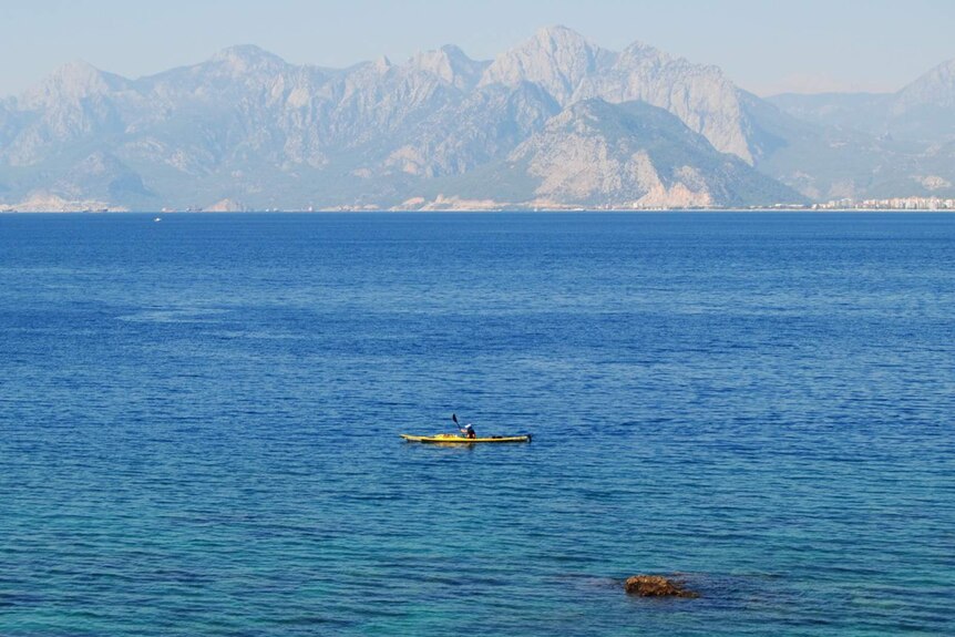 Sandy Robson paddles a bright yellow kayak in an otherwise empty sea off the coast of Turkey.