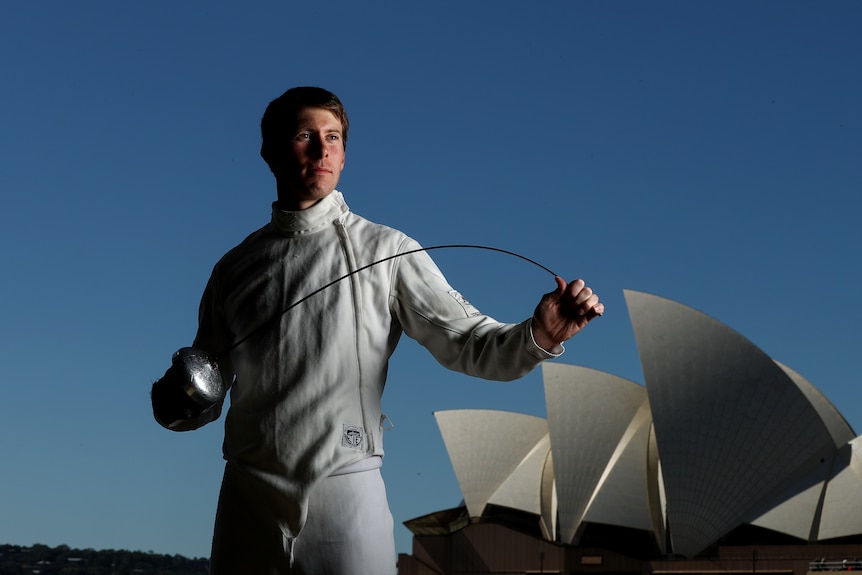 Edward Fernon poses with a fencing sword with the Opera House in the background..