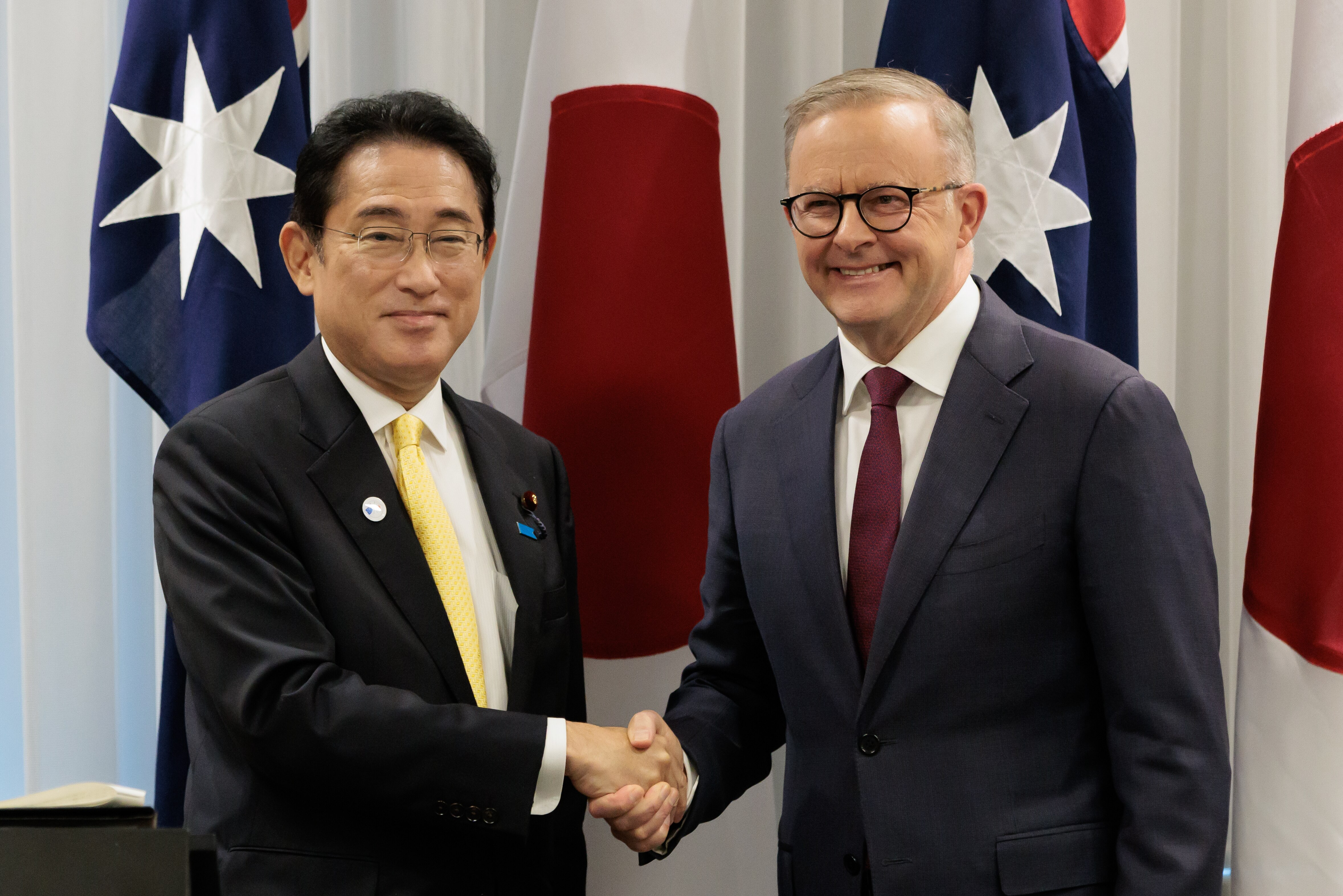 Kishida Fumio and Anthony Albanese shake hands during a leaders' meeting in Perth. They are dressed in suits