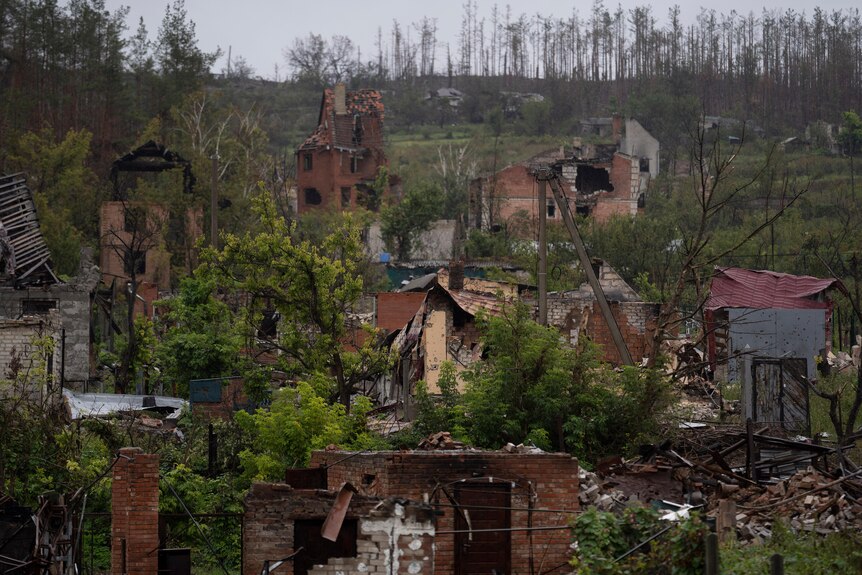 Un côté d'une colline est couvert de débris de maisons détruites dans une guerre