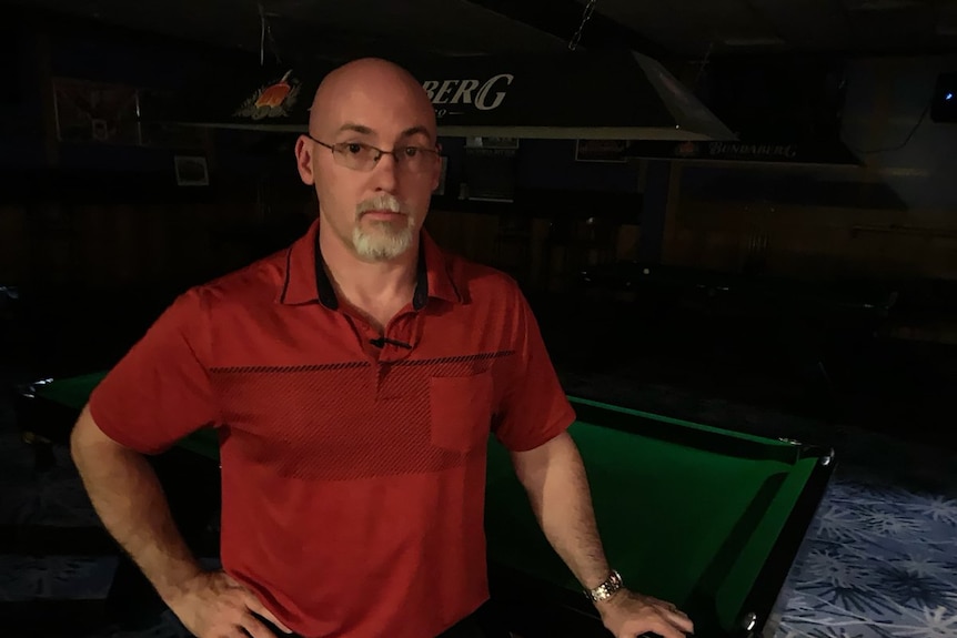 Man leaning on a snooker table.