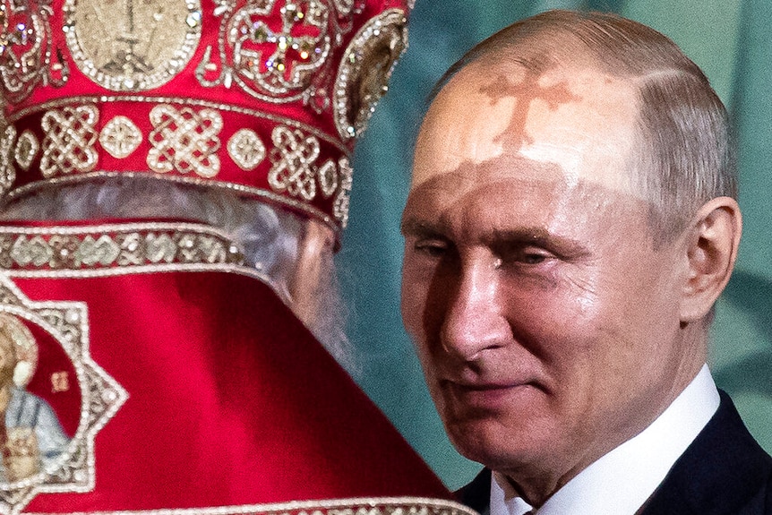 Putin seen with an orthodox priest, who has his back toward the camera.