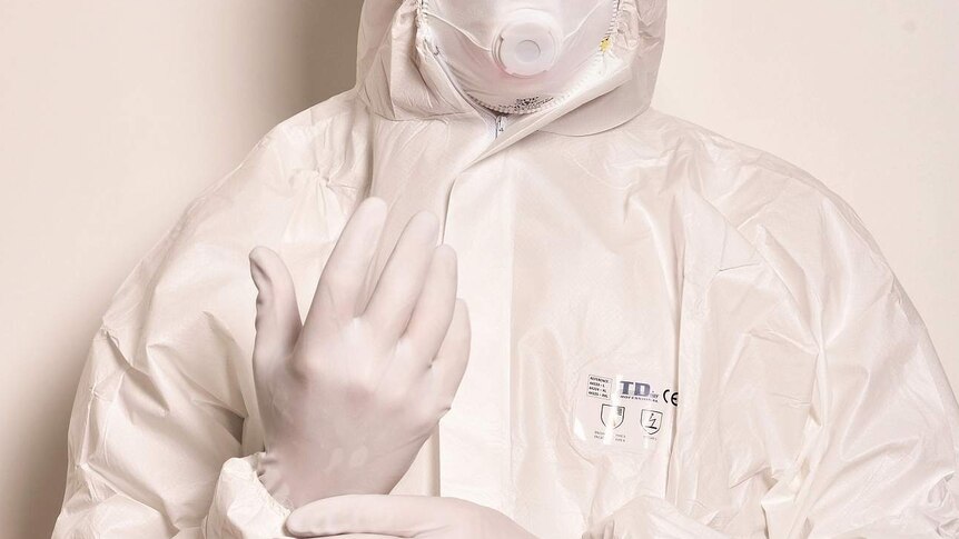 Person in protective suit with respiratory mask and gloves.