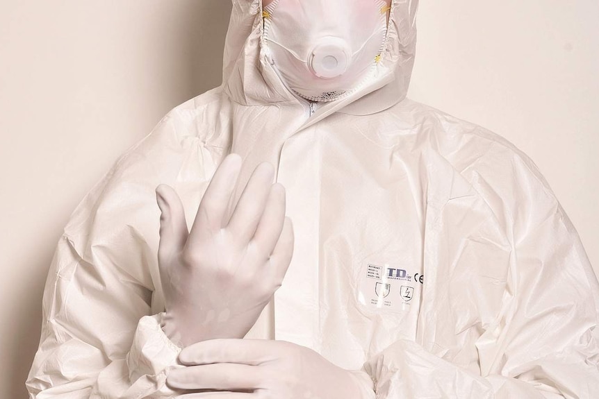 Person in protective suit with respiratory mask and gloves.