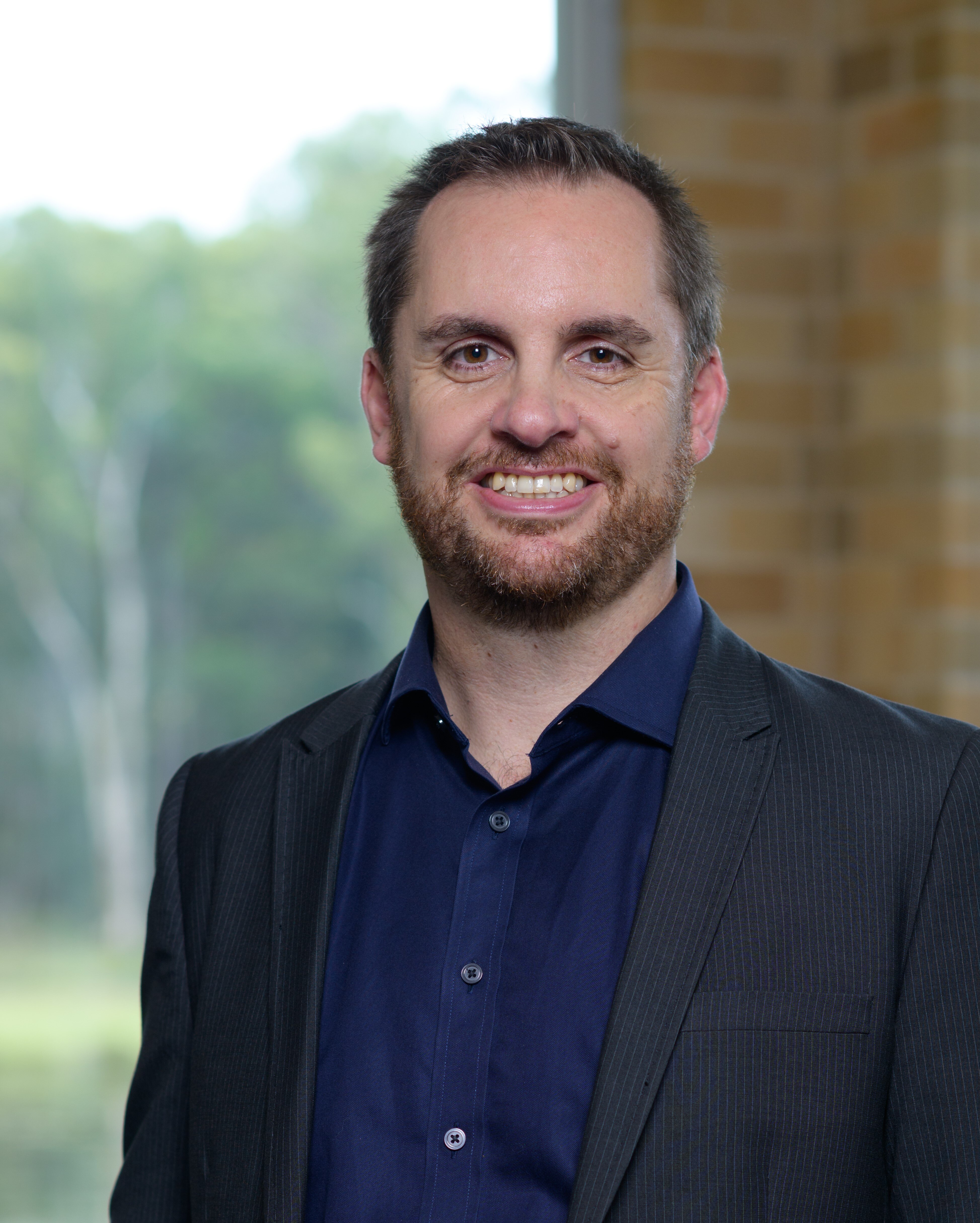 Portrait of a middle-aged Caucasian man with a beard and a broad smile. 