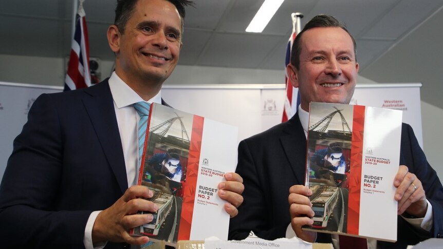 Ben Wyatt and Mark McGowan smile while holding the budget papers.