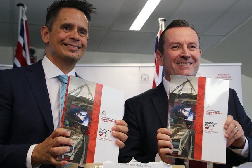 Ben Wyatt and Mark McGowan smile while holding the budget papers.