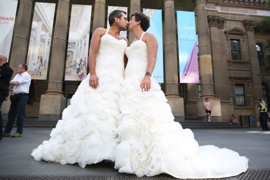 Melbourne couple George and Luke wear wedding dresses and kiss in the centre of melbourne