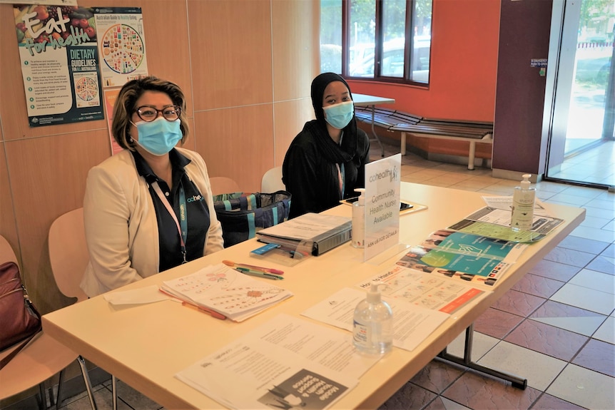 An image of two female community members sitting at a "health concierge" table.