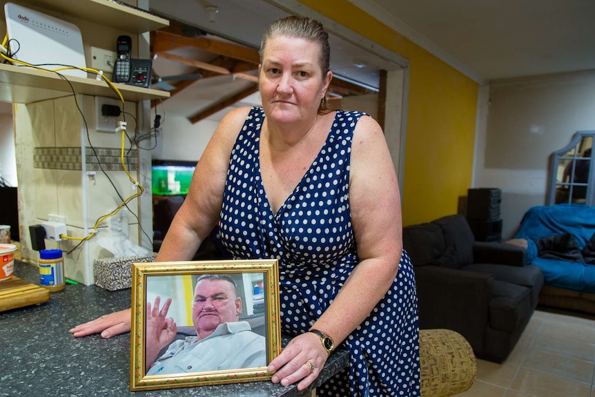 Louise Holland from Sydenham holds a photo of her ill husband before he died.