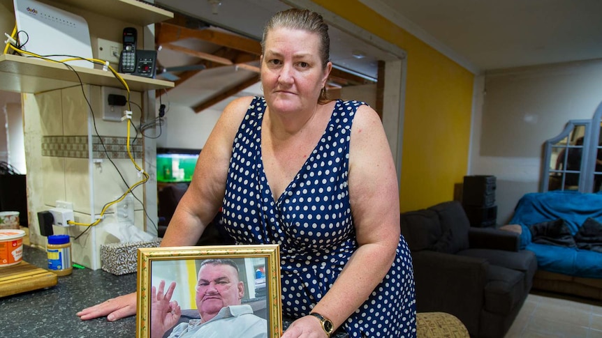 Louise Holland from Sydenham holds a photo of her ill husband before he died.