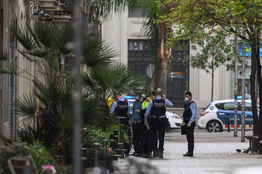 A group of police officers in Spain stand in the street wearing face masks in Barcelona during the coronavirus pandemic.