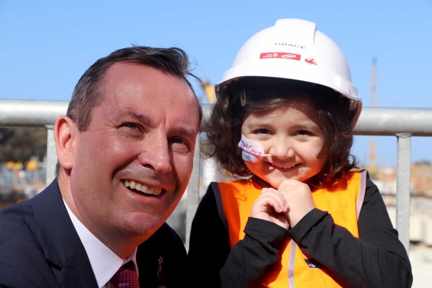 Mark McGowan headshot with Grace wearing a hard hat looking delighted.