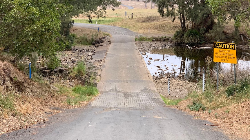 Image of a dry river crossing, with a dry road, and low creek either side.