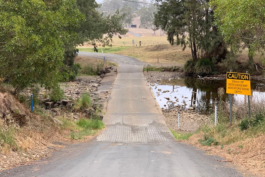 Image of a dry river crossing, with a dry road, and low creek either side.