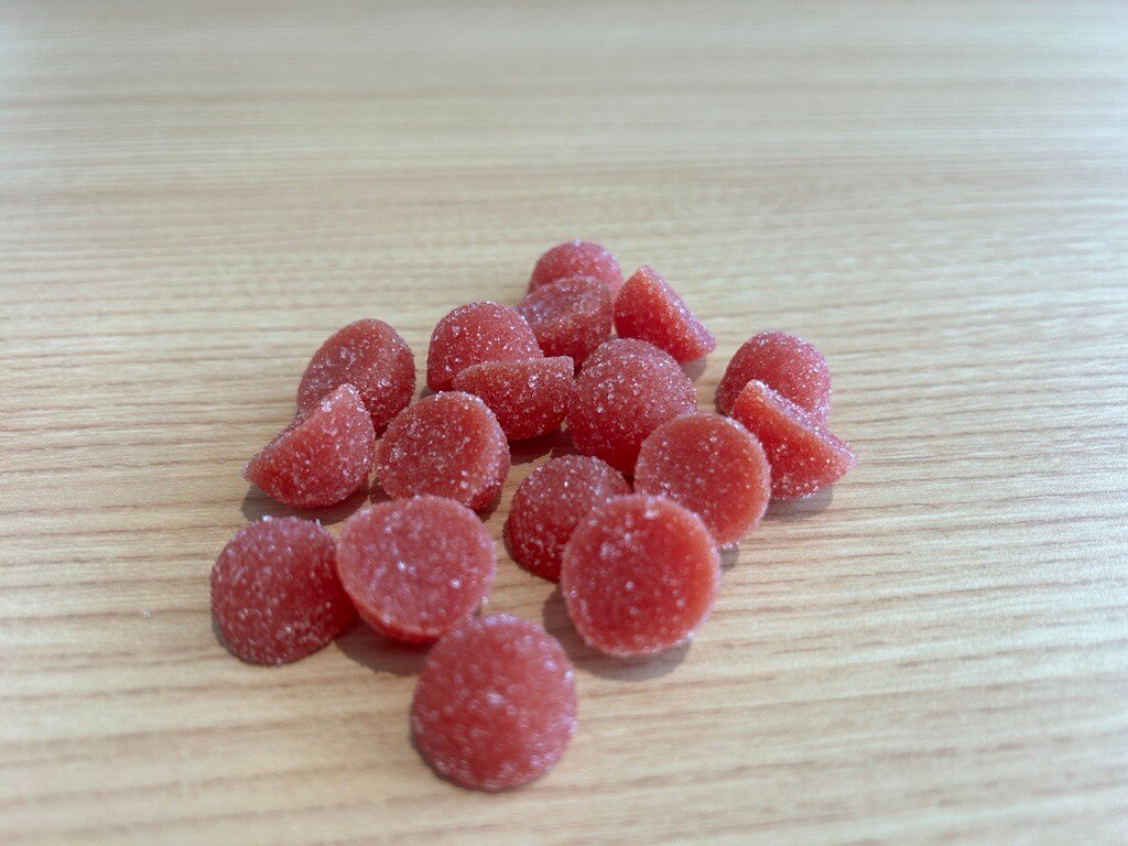 Multiple red gummy vitamins sitting on a brown table top.