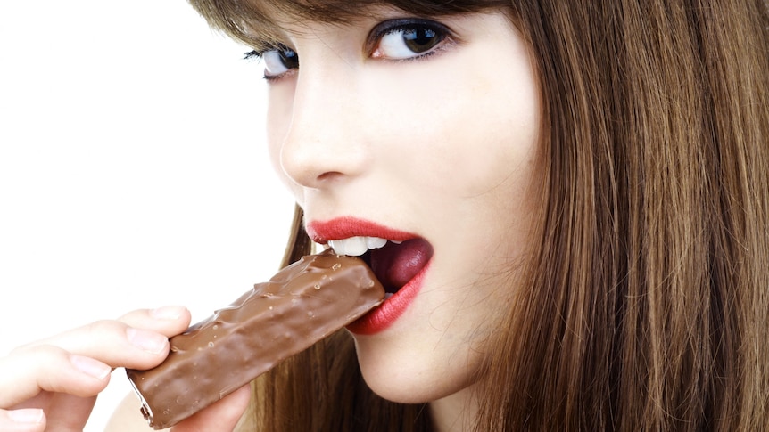 Sexy woman eating a bar of chocolate