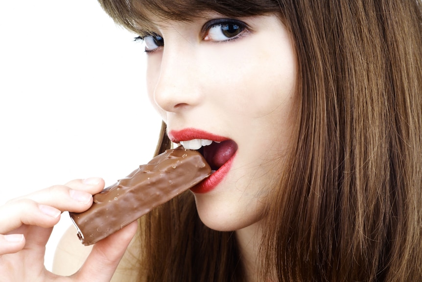 Sexy woman eating a bar of chocolate
