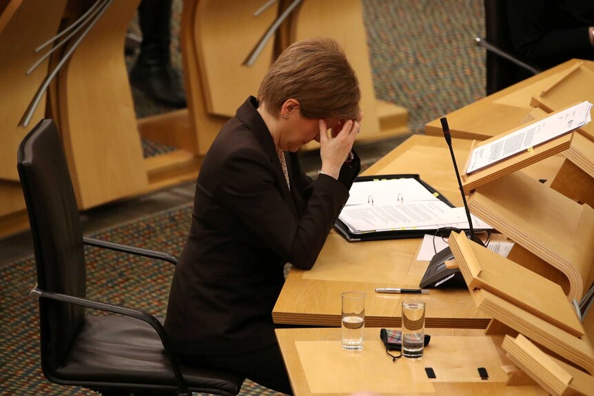 Nicola Sturgeon places her head in her hands in Scottish Parliament.