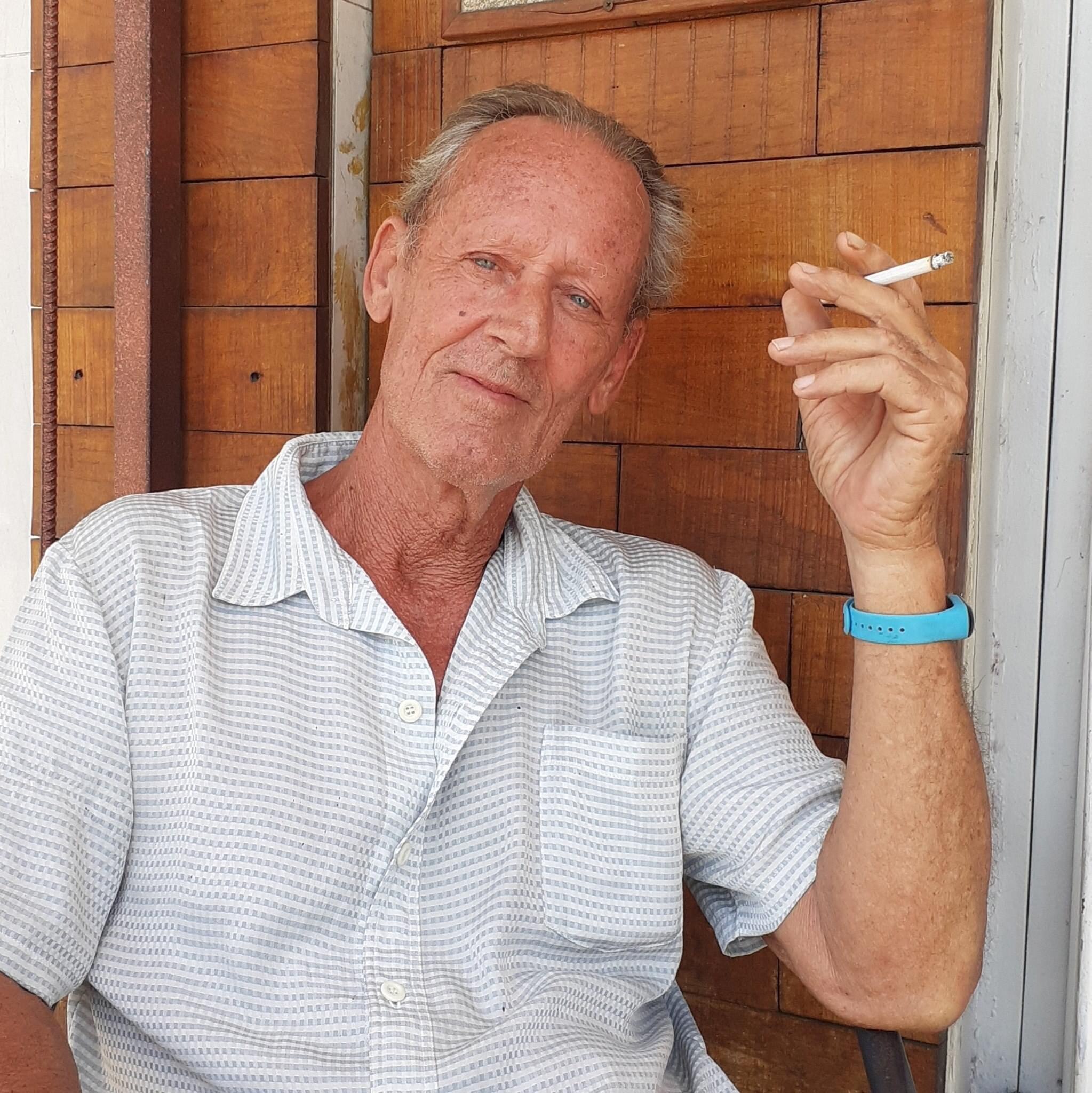 A shirtless man holds a cigarette 