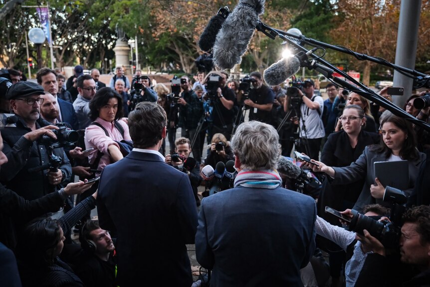 Two men surrounded by journalists and camera operators 