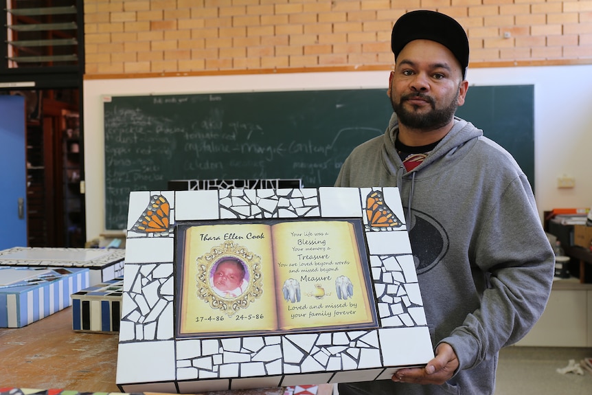 Dwayne Cook holds the headstone he made for his sister