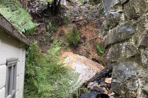 A large boulder is seen at the back of a house.