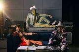Jimmie Allen, Mickey Guyton and Orville Peck posing in colourful outfits, Orville wearing a face mask