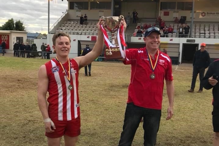 a man in a red and white shirt and a man in a red holding a trophy