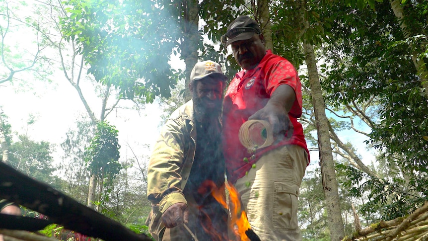 Peter Diria and Joe Alu burn infested coffee berries in an open fire