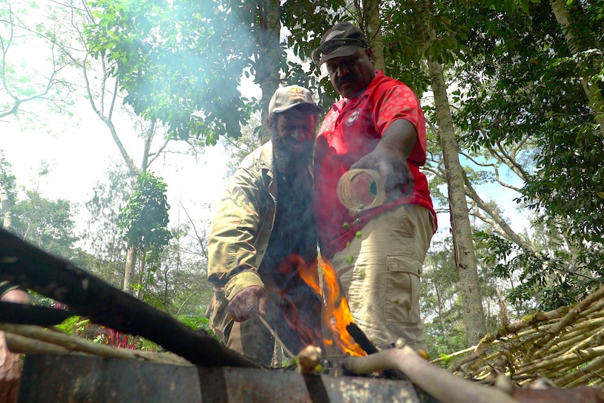 Peter Diria and Joe Alu burn infested coffee berries in an open fire