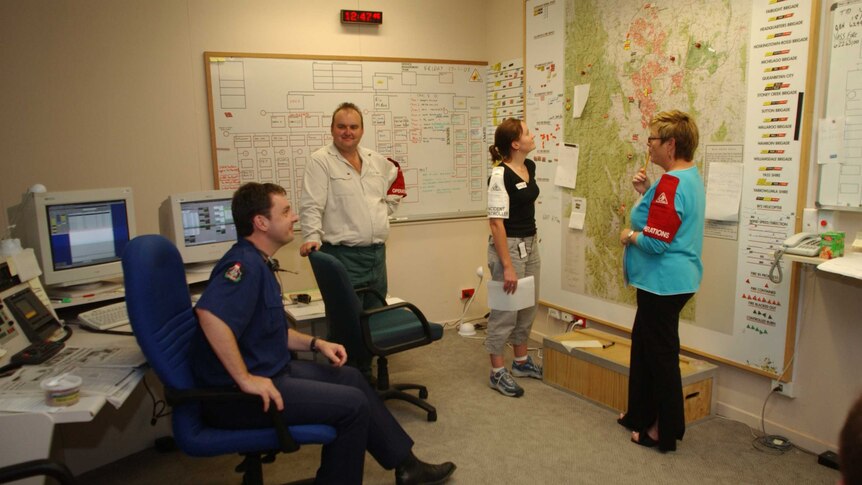 Four officers having a discussion in front of a map in Curtin as the bushfire unfolds.